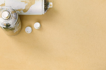 Some used orange aerosol spray cans and nozzles with paint drips lies on a blanket of soft and...