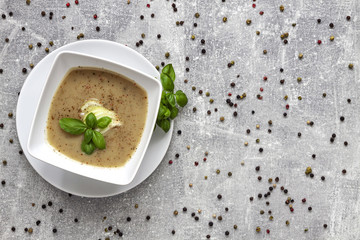 Onion soup, fresh basil and colored pepper on a concrete kitchen table
