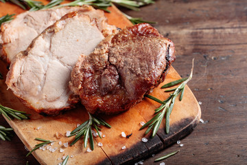 Oven-baked pork with rosemary and spices on a wooden table.