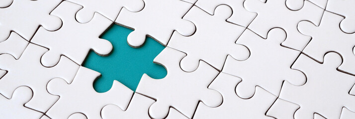 Close-up texture of a white jigsaw puzzle in assembled state with missing elements forming a blue...