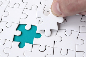 The human hand fills the last missing elements of the surface from the jigsaw puzzle. The concept...