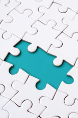 Close-up texture of a white jigsaw puzzle in assembled state with missing elements forming a blue...