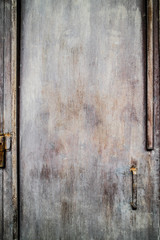 Gray metal door, a little bit rusty, with a handle.