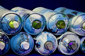 Still life with a large number of used colorful spray cans of aerosol paint lying on the treated...