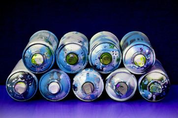 Still life with a large number of used colorful spray cans of aerosol paint lying on the treated...