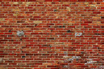 Weathered repaired red brick wall of old house facade as colorful abstract background.