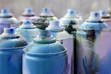 A lot of dirty and used aerosol cans of bright blue paint. Macro photograph with shallow depth of...