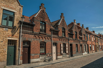 Brick facade of houses in typical Flanders’s style and bicycle, in street of Bruges. With many canals and old buildings, this graceful town is a World Heritage Site of Unesco. Northwestern Belgium.