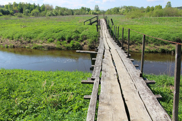 Old wooden bridge over river in summer countryside