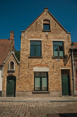 Brick facade of old houses and doors with blue sky, in an empty street of Bruges. With many canals and old buildings, this graceful town is a World Heritage Site of Unesco. Northwestern Belgium.