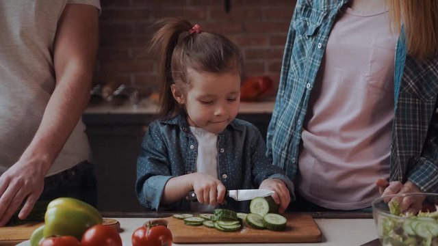 Closeup of the cute little girl, halping parents wth prepearing food.