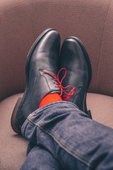 The legs of a man in shoes with red laces and in red socks are impressively thrown one on top of another, a kind from the first person