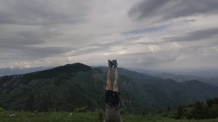 Man doing a handstand outdoors on a cliff