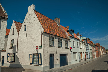 Brick facade of old houses with a blue sunny sky in an empty street of Bruges. With many canals and old buildings, this graceful town is a World Heritage Site of Unesco. Northwestern Belgium.