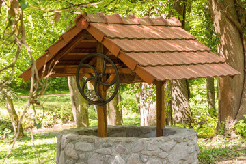 a stone well with a roof in the middle of a forest