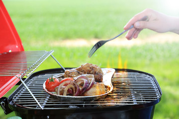 Grilowanie mięsa i warzyw na grilu turystycznym w ogrodzie.