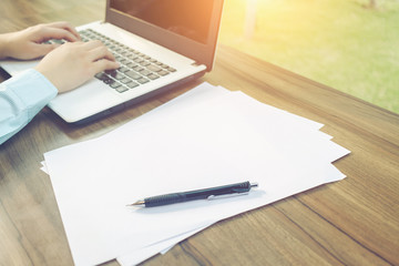 Close-up of business female working with laptop make a note document and smartphone in coffee shop like the background.