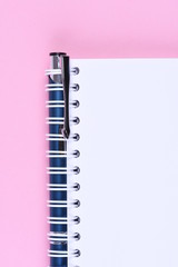 Top view of blank note paper book with pen on pink background
