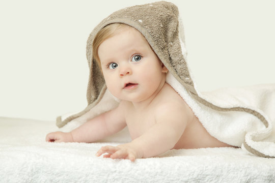 Adorable baby covered with bath towel, studio shot