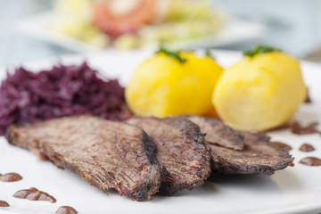 deutschen Sauerbraten mit Rotkohl auf einem Teller