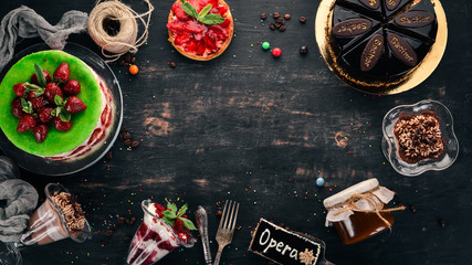Assortment of desserts. On a black wooden background. Top view. Copy space.