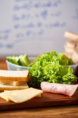 Back to School concept, school supplies, biscuits, packed lunch and lunchbox over white chalkboard, selective focus.