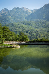artificial lake in the mountains with Sunny day, forested mountains reflected in the water