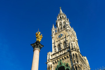 Fototapeta na wymiar Marian column (1639) or Mariensaule with statue of Virgin Mary on the top and Neues Rathaus, Munich, Germany