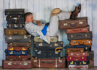 the man is sitting on old suitcases