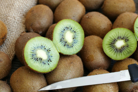 kiwi fruit cut into two pieces with a knife on a wooden floor
