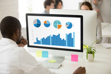 African businessman analyzing graphic data charts graphs of marketing sales project performance on...