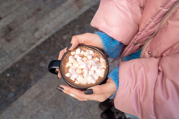 cup of cocoa with marshmallow in hands