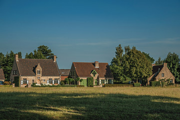 Cottages and trees in front of cultivated fields at the late afternoon light, next the village of Damme. A quiet and charming countryside old village near Bruges. Northwestern Belgium.
