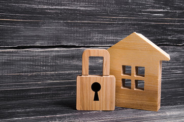 Obraz na płótnie Canvas Wooden house with a padlock. House with a lock. Security and safety, collateral, loan for a mortgage. Confiscation of property for debts. Safety and alarm system. Buying a new home.
