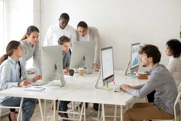 Focused busy multiracial business people working online on computers in coworking space, diverse...