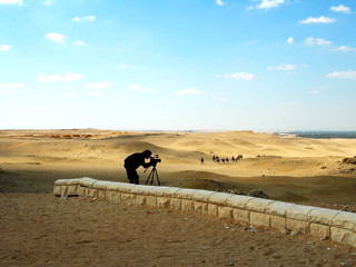 The operator shoots video on a tripod in the desert Bedouin. Shooting video. Silhouette, concept, daylight bright light. Egypt.