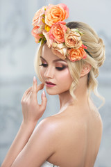 Beauty portrait of a cute blonde girl with a wreath of tea roses.