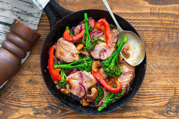 Sichuan pork, broccoli, red pepper and cashew stir-fry in a frying pan - top view