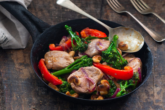 Sichuan pork, broccoli, red pepper and cashew stir-fry in a frying pan