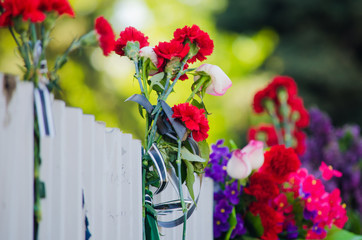 Red flowers with black tape wrapped around them on the fence at the place of tragedy