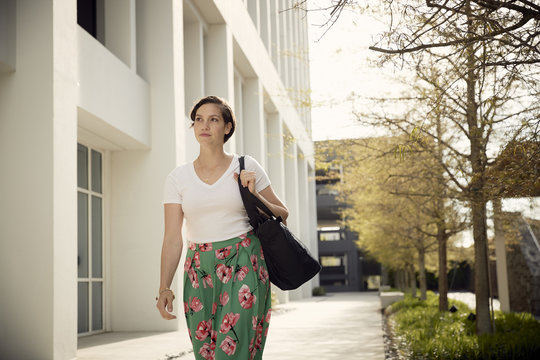 Woman looking away while walking by building in city