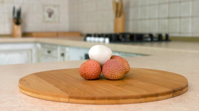 Close up of several whole lychee. Rotating camera with white kitchen on the background. Dolly-shot.