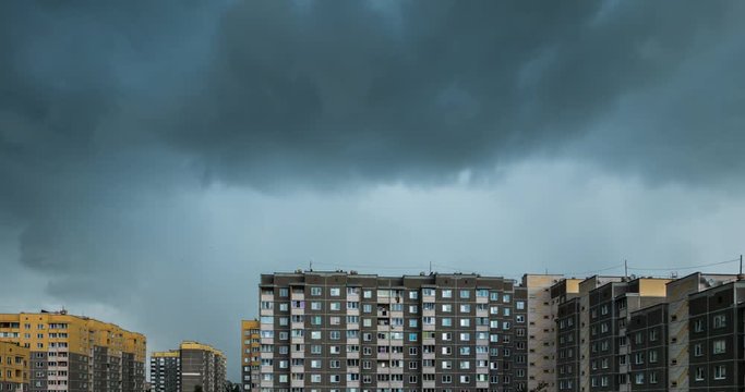 Time lapse clip of white fluffy rolling clouds before storm against the background of yellow multi-storey apartment building