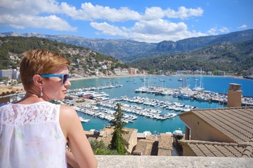 Fototapeta na wymiar woman with blue sunglasses looking at Port de Soller rooftops, Mallorca, Spain