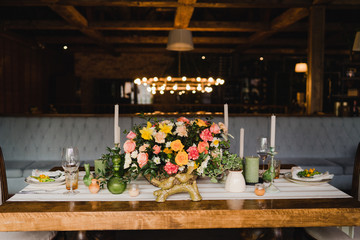 Coziness and style. Modern evetn design. Decorations and laying on the dining table. Beautiful colorful floral composition. Vintage plates, glasses, natural linen tablecloth.