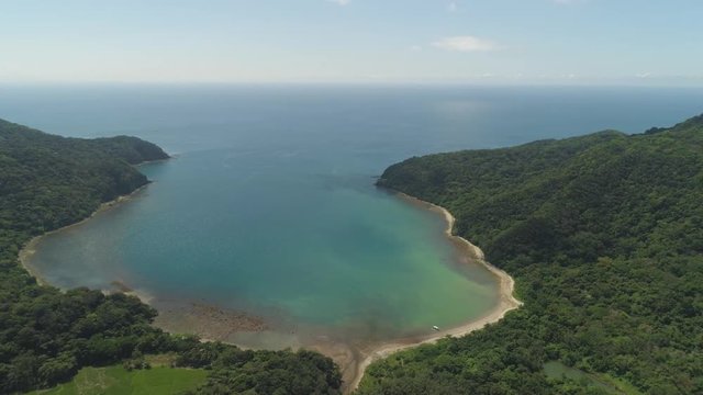 Aerial view of tropical beach in bay with turquoise water. Siwangag Cove. Coast of tropical island Palau with mountains covered rainforest. Santa Ana, province of Cagayan, Philippines.