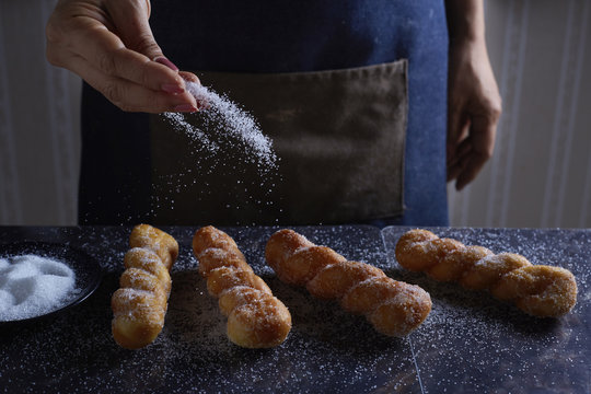 Midsection of woman sprinkling sugar on shakoy at table