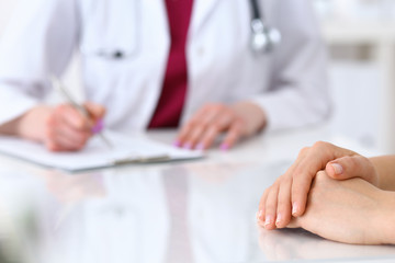 Female doctor filling up  an application form while consulting patient. Just hands. Medicine and health care concept