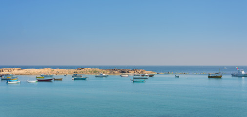 Calm Mediterranean sea with clear sky, small boats and small island at the coast of Alexandria, Egypt