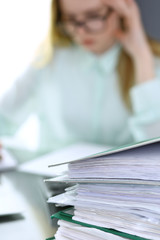 Bookkeeper or financial inspector  making report, calculating or checking balance. Binders with papers closeup. Audit and tax service concept. Green colored image background 